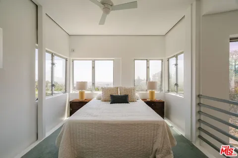 a bedroom with a bed and large windows