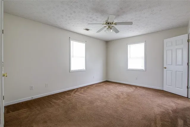an empty room with windows and chandelier fan