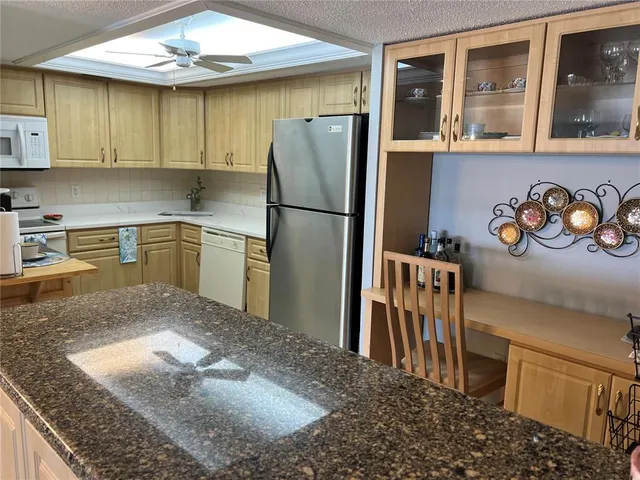 a kitchen with stainless steel appliances granite countertop a refrigerator a stove and a sink