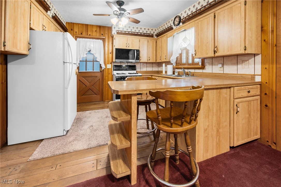 6944 Rolling Ridge Road Northeast Canton, OH 44721 - Photo 9 of 27 Kitchen with white appliances, ceiling fan, a breakfast bar, hardwood / wood-style floors, and light brown cabinets