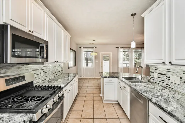 a large kitchen with stainless steel appliances granite countertop a stove a sink and a microwave