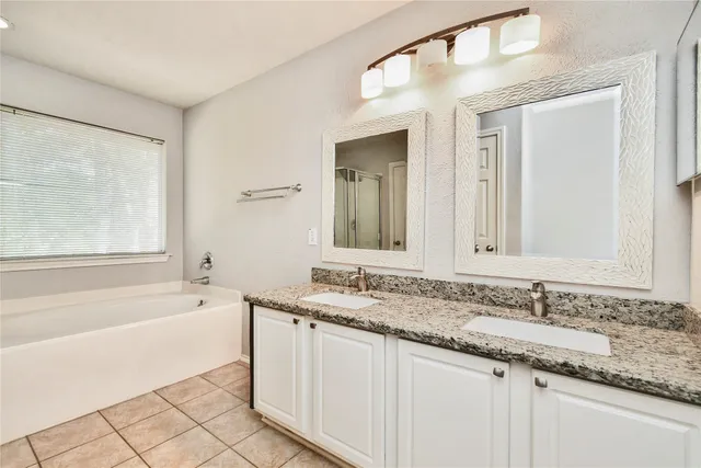 a bathroom with a granite countertop sink mirror and a bathtub