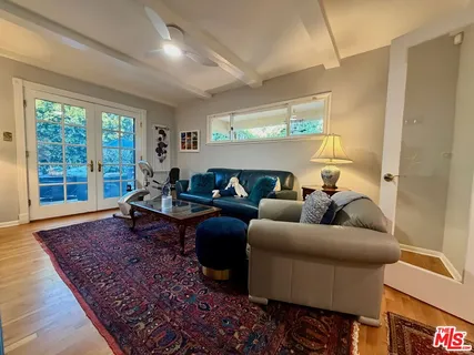 a living room with furniture a flat screen tv and floor to ceiling window