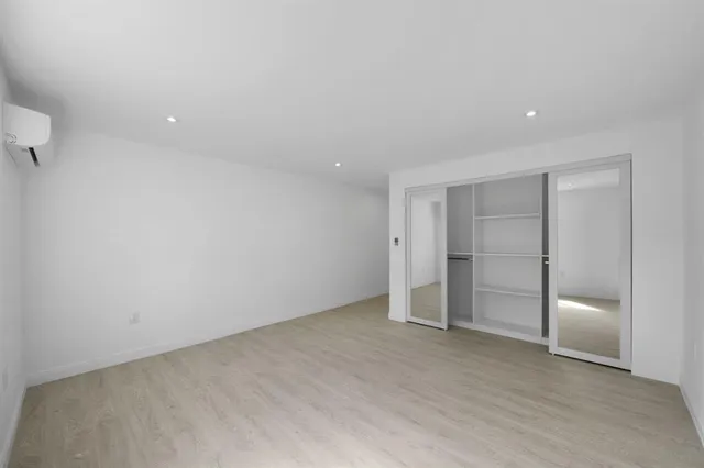a view of an empty room with wooden floor and a bathroom