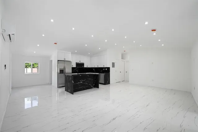 a view of kitchen with stainless steel appliances granite countertop a refrigerator and a stove top oven