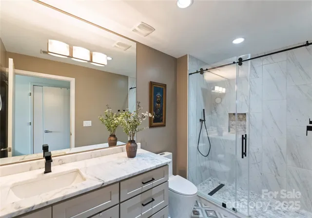 a bathroom with a granite countertop sink a toilet and shower
