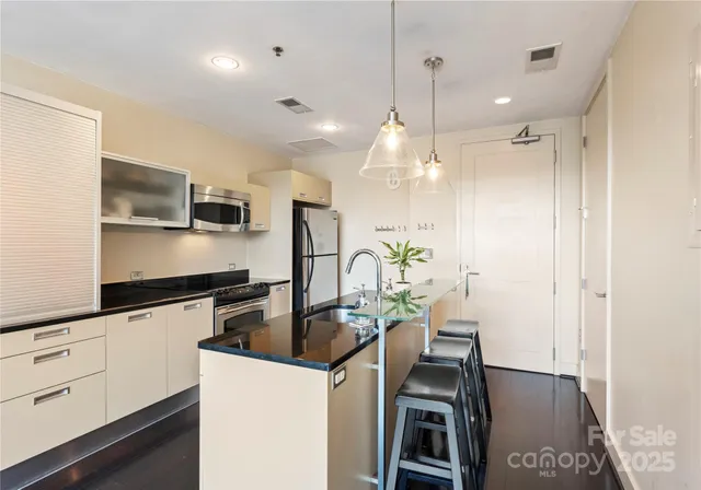 a kitchen with granite countertop a stove a sink a refrigerator a stove a dining table and chairs with wooden floor