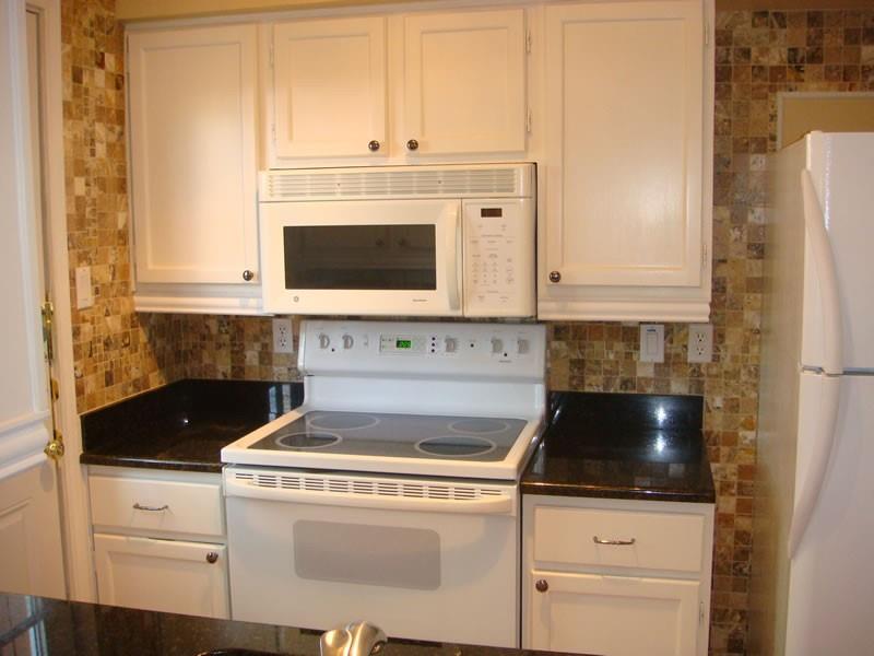 4000 Rawlins Street, Unit 105 Dallas, TX 75219 - Photo 14 of 26 a kitchen with granite countertop white cabinets and stainless steel appliances