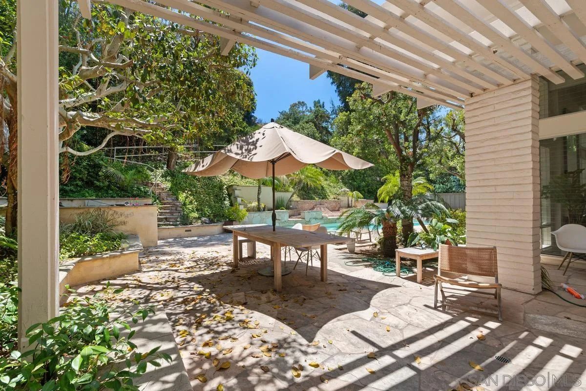6729 Avenida Andorra La Jolla, CA 92037 - Photo 19 of 27 a view of a patio with a dining table and chairs under an umbrella with a small yard
