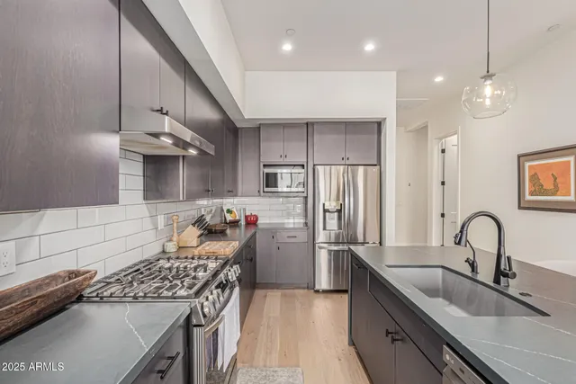 a kitchen with stainless steel appliances granite countertop a sink stove and refrigerator