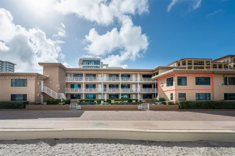 a front view of a building with lot of cars and trees