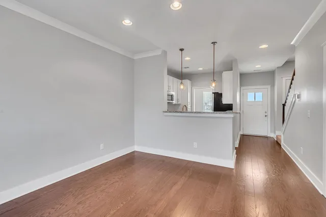an empty room with wooden floor and kitchen