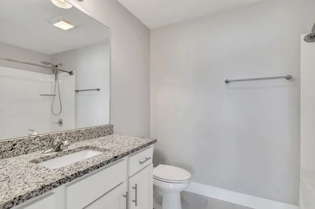 a bathroom with a granite countertop sink a toilet and a shower