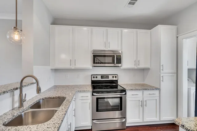 a kitchen with stainless steel appliances granite countertop a sink a stove a microwave and cabinets