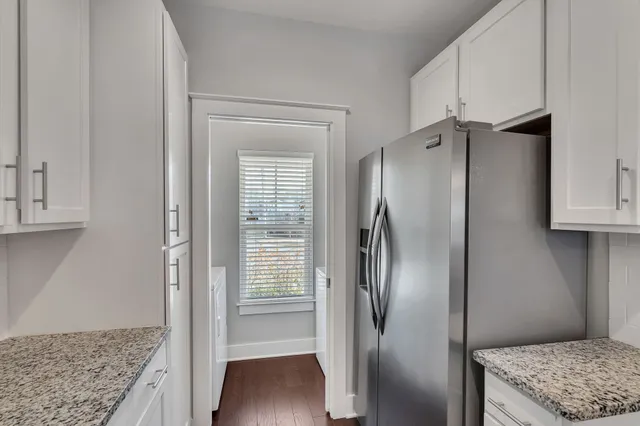a view of a kitchen with refrigerator and wooden floor