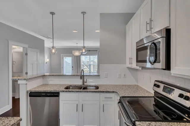 a kitchen with granite countertop a sink stainless steel appliances and white cabinets