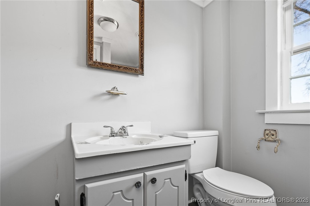 107 North 12th Street Erwin, NC 28339 - Photo 28 of 40 a bathroom with a toilet a sink a mirror and a window