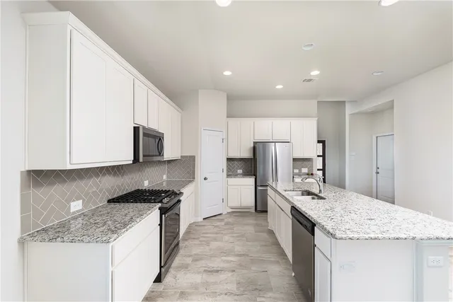 a large kitchen with stainless steel appliances kitchen island granite countertop a large counter top and a stove top oven