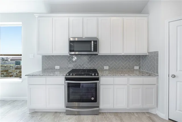 a kitchen with white cabinets and stainless steel appliances