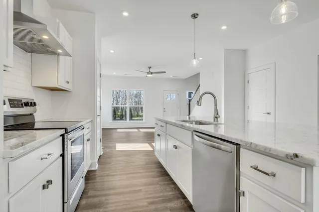 a large kitchen with stainless steel appliances granite countertop a lot of counter space and wooden floors