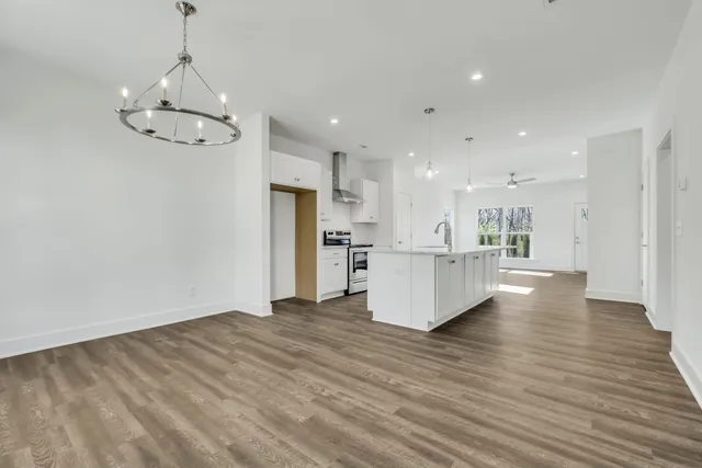 a view of a kitchen with a refrigerator wooden floor and a chandelier