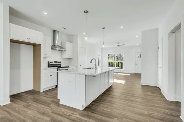a large white kitchen with white cabinets and wooden floor