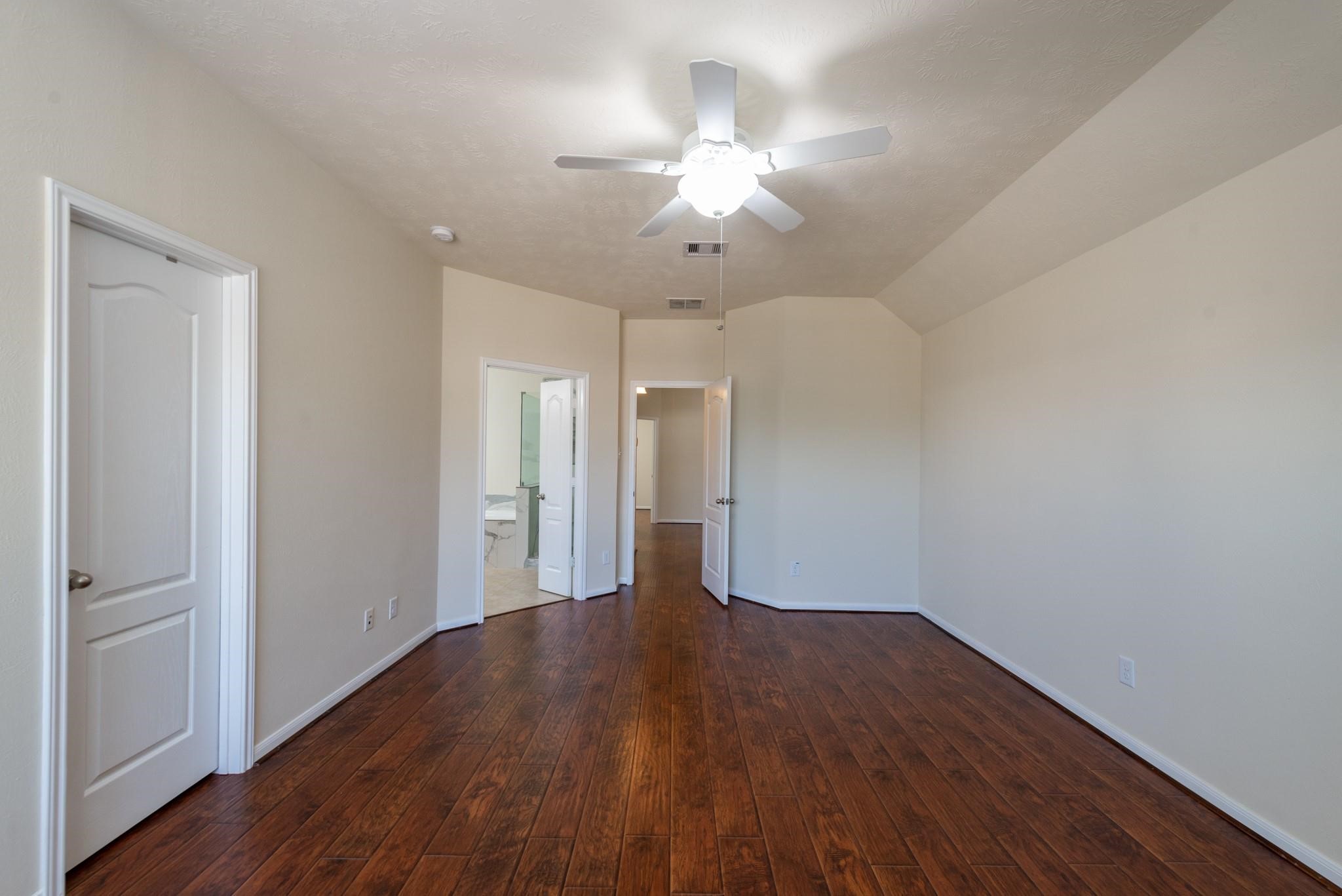 6402 Addlestone Ridge Lane Katy, TX 77494 - Photo 12 of 25 Spacious primary suite featuring rich wood-look flooring, high ceilings, and plenty of room for a king-size bed and additional furniture. The private en-suite bathroom provides a relaxing retreat, while the generous layout creates a comfortable space to unwind at the end of the day.