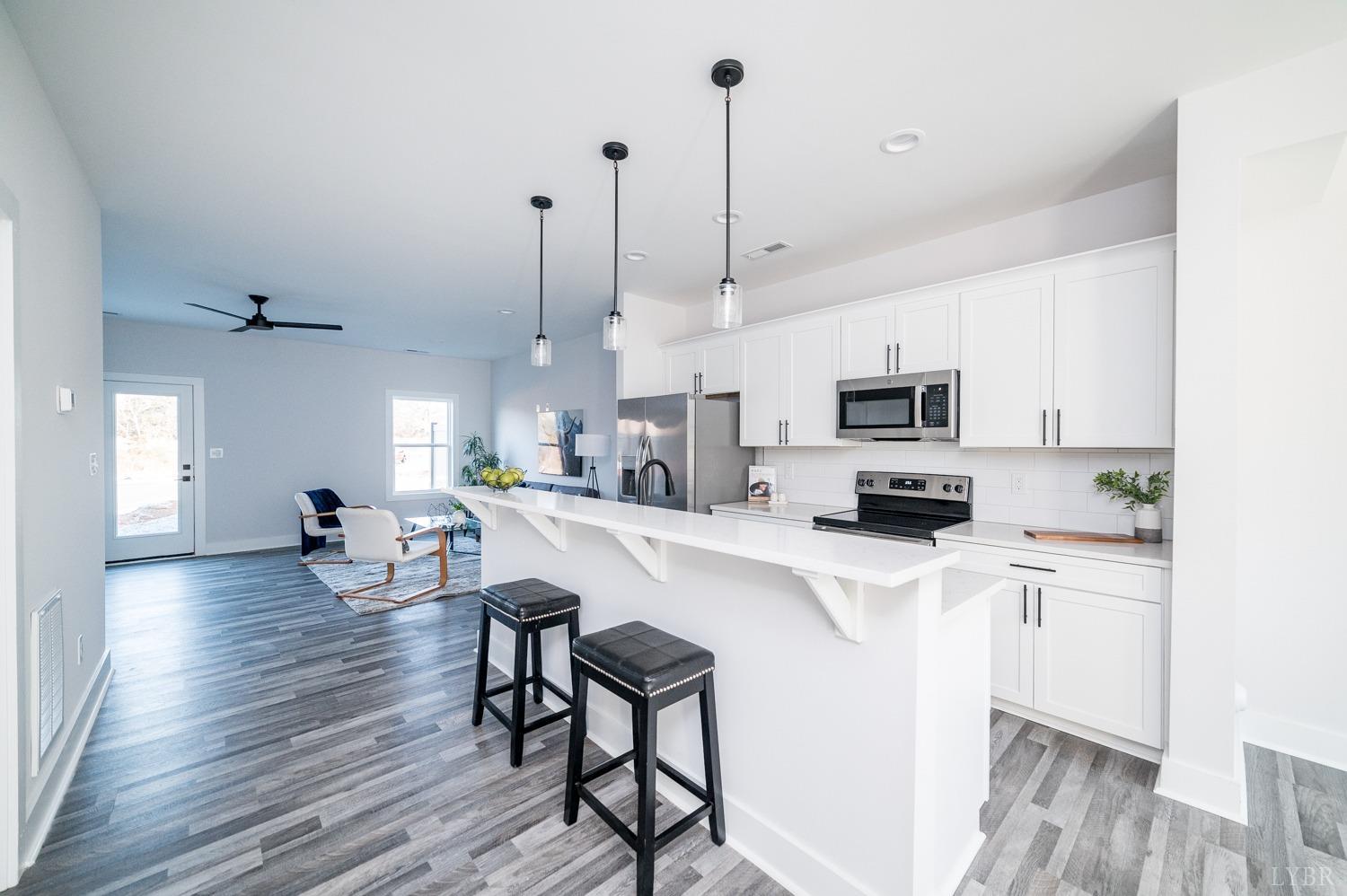 71 Allure Drive Rustburg, VA 24588 - Photo 11 of 56 a kitchen with stainless steel appliances kitchen island granite countertop a stove a sink a microwave a dining table and chairs with wooden floor