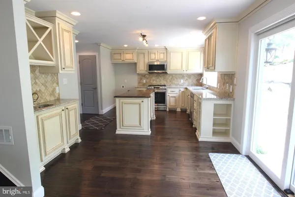 a open kitchen with white cabinets and wooden floor