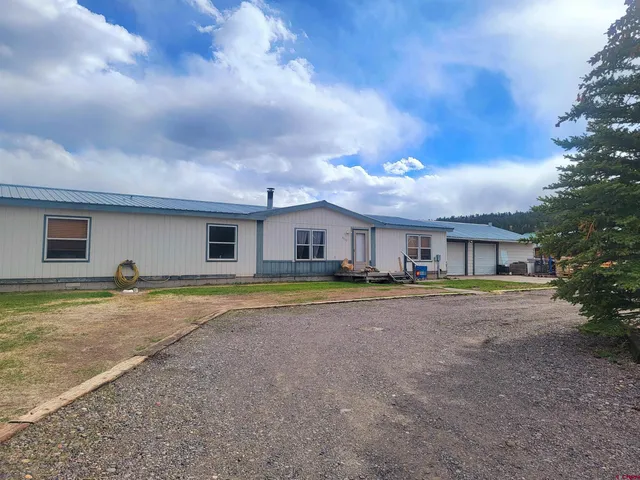 a view of a house with a yard and large tree