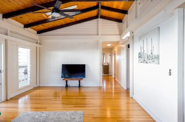 a large white kitchen with a lot of counter space and wooden floor