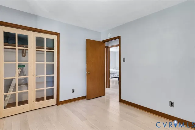 a view of an empty room with wooden floor and windows