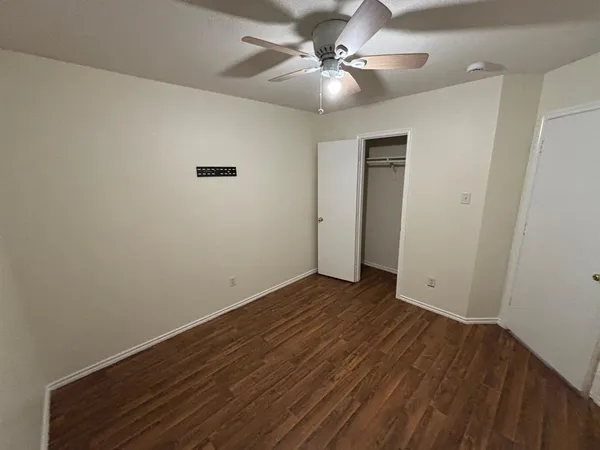 an empty room with wooden floor and a ceiling fan