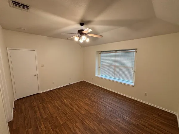 a view of empty room with wooden floor and fan