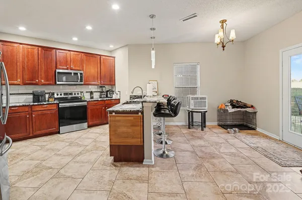 a kitchen with stainless steel appliances granite countertop a stove top oven a sink counter space and a view of living room
