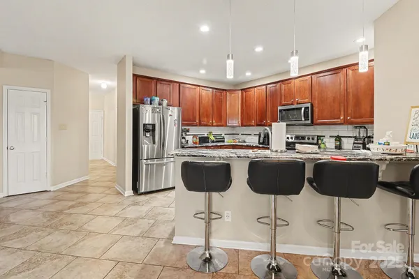 a kitchen with granite countertop a refrigerator and a stove top oven