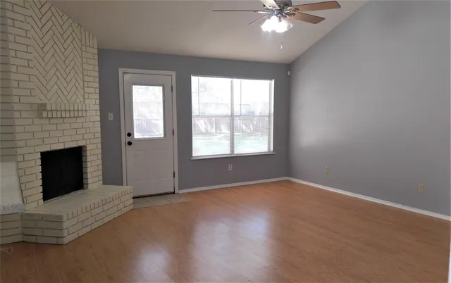 an empty room with windows and fireplace