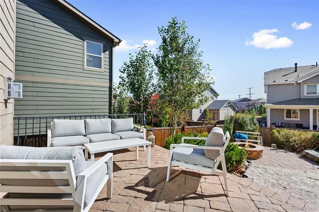 a view of a patio with couches table and chairs with wooden fence and plants