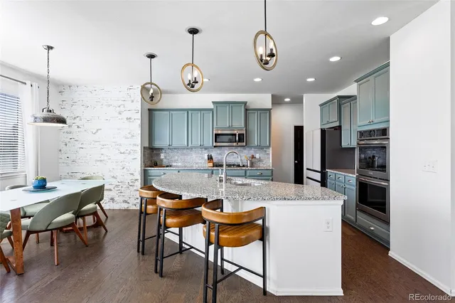 a kitchen with stainless steel appliances kitchen island granite countertop a table chairs and a refrigerator