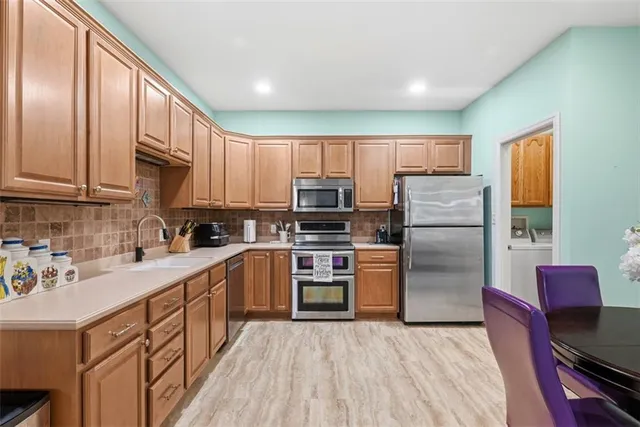 a kitchen with kitchen island granite countertop a stove top oven a sink dishwasher a refrigerator cabinets and wooden floor