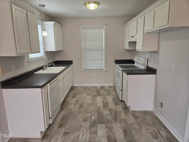 a kitchen with granite countertop a sink stove and cabinets