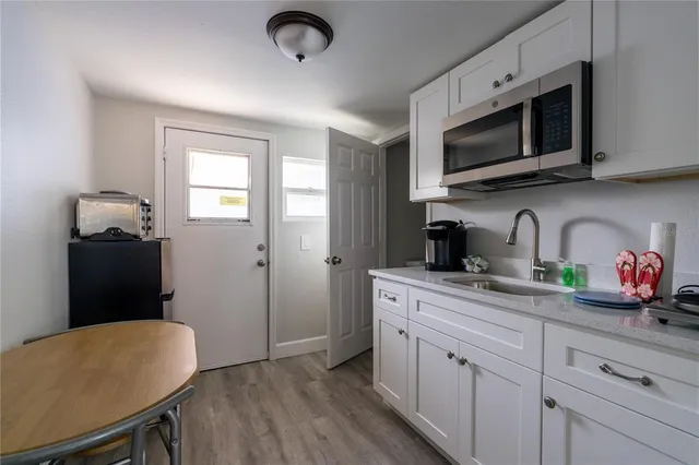 a kitchen with stainless steel appliances granite countertop a refrigerator a sink dishwasher a stove microwave and a dining table with wooden floor