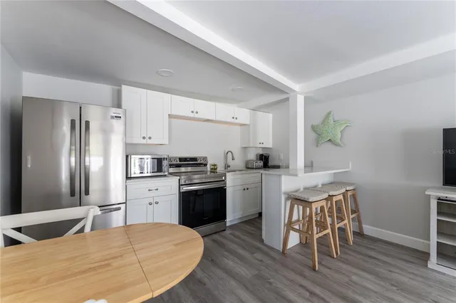 a kitchen with granite countertop a refrigerator stove top oven and sink