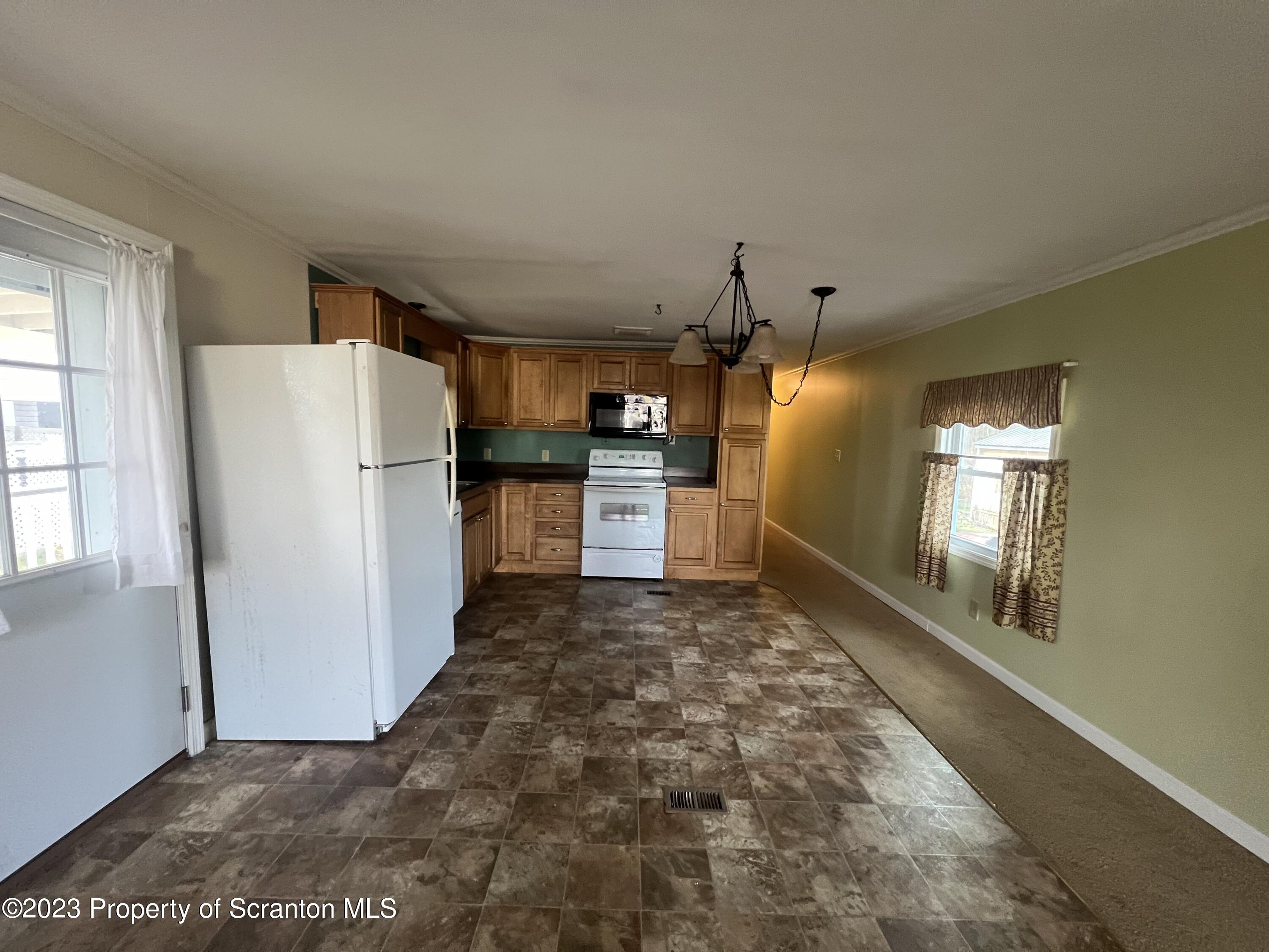 50 Mt Laurel L 50 Spring Brook Moscow, PA 18444 - Photo 6 of 13 a view of a refrigerator in kitchen and an empty room with wooden floor and a window