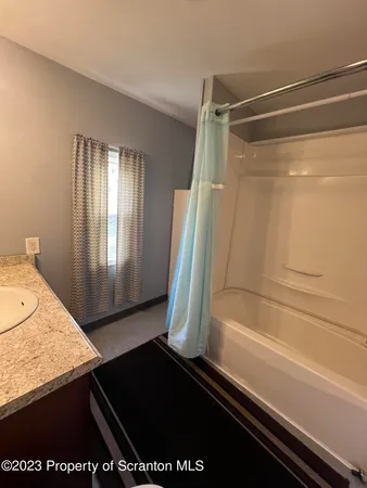 a bathroom with a granite countertop sink and a shower