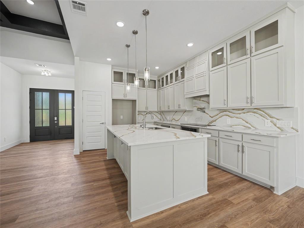 328 Slimp Bluff Azle, TX 76020 - Photo 10 of 30 Contemporary kitchen featuring an island with a sink, white cabinetry, integrated appliances, and a marble-patterned backsplash