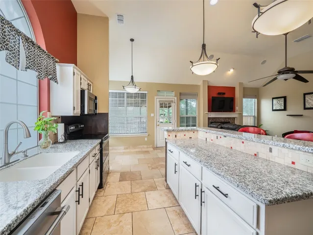a kitchen with stainless steel appliances granite countertop a sink counter space cabinets and a chandelier