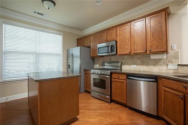 a kitchen with stainless steel appliances granite countertop a stove a sink and a microwave