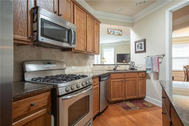 a kitchen with stainless steel appliances granite countertop a stove microwave and sink