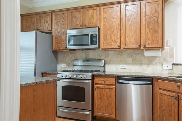 a kitchen with stainless steel appliances granite countertop a stove a microwave and a refrigerator